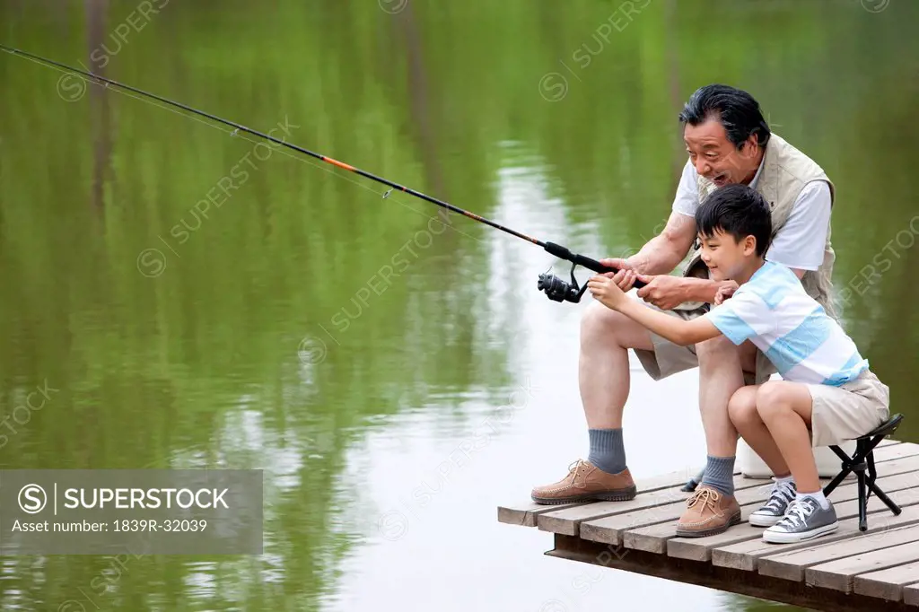 Grandfather teaching grandson fishing