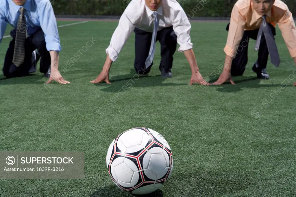 Businessmen On A Field Preparing To Run To A Soccer Ball