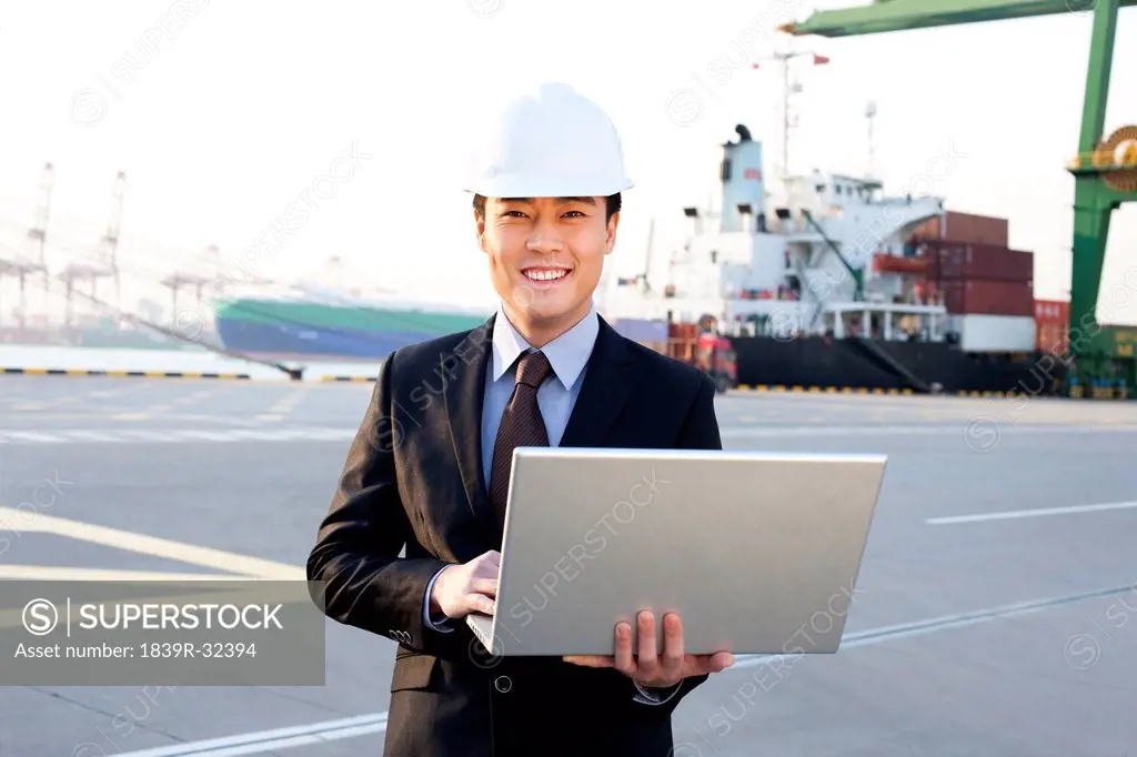 businessman using a laptop at a shipping port
