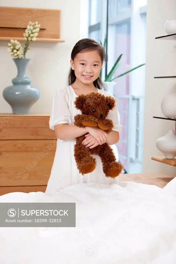 Little girl in bedroom with teddy bear in hand
