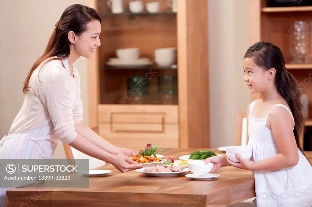 Mother and daughter setting the table