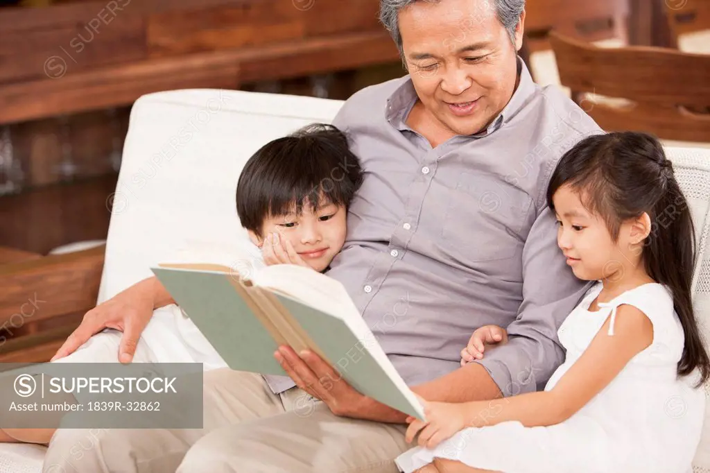 Grandfather reading a book with grandchildren