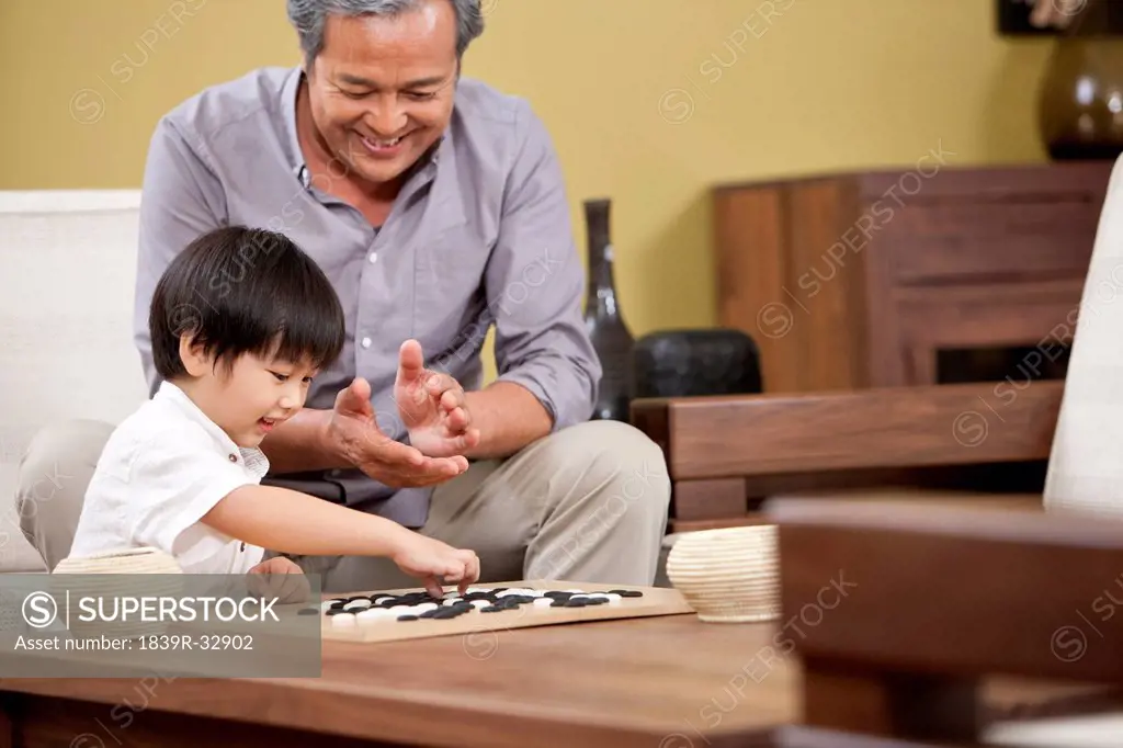 Little boy playing Chinese game of Go with grandfather