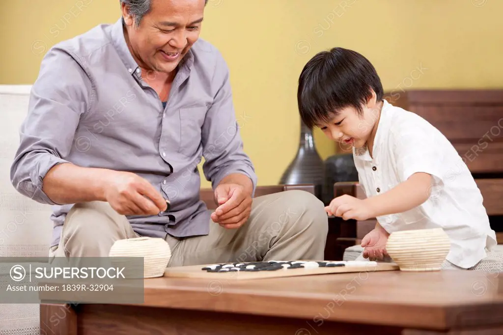 Little boy playing Chinese game of Go with grandfather