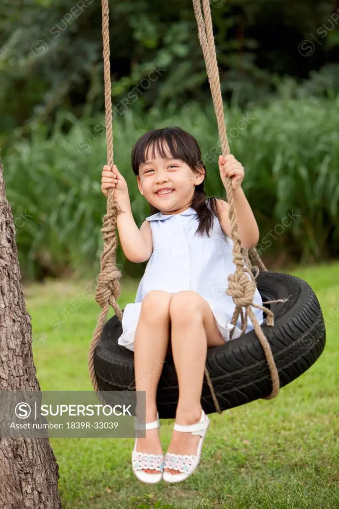 Excited little girl playing on a swing
