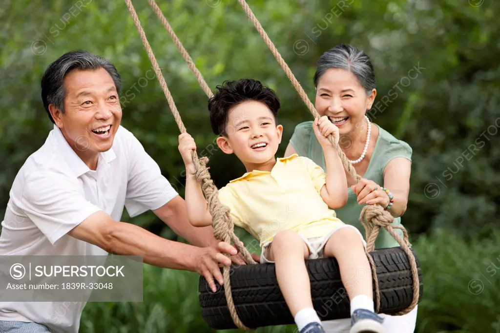 Little boy playing on a swing with grandparents