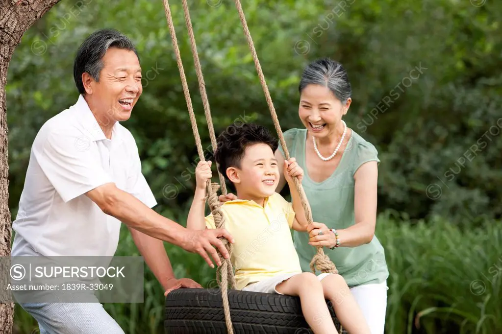 Grandparents and grandson playing on a swing