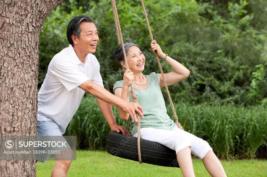 Happy senior couple playing on a swing