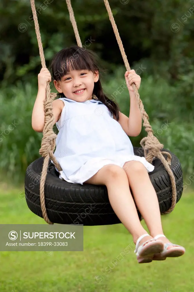 Cute little girl playing on a swing outdoors
