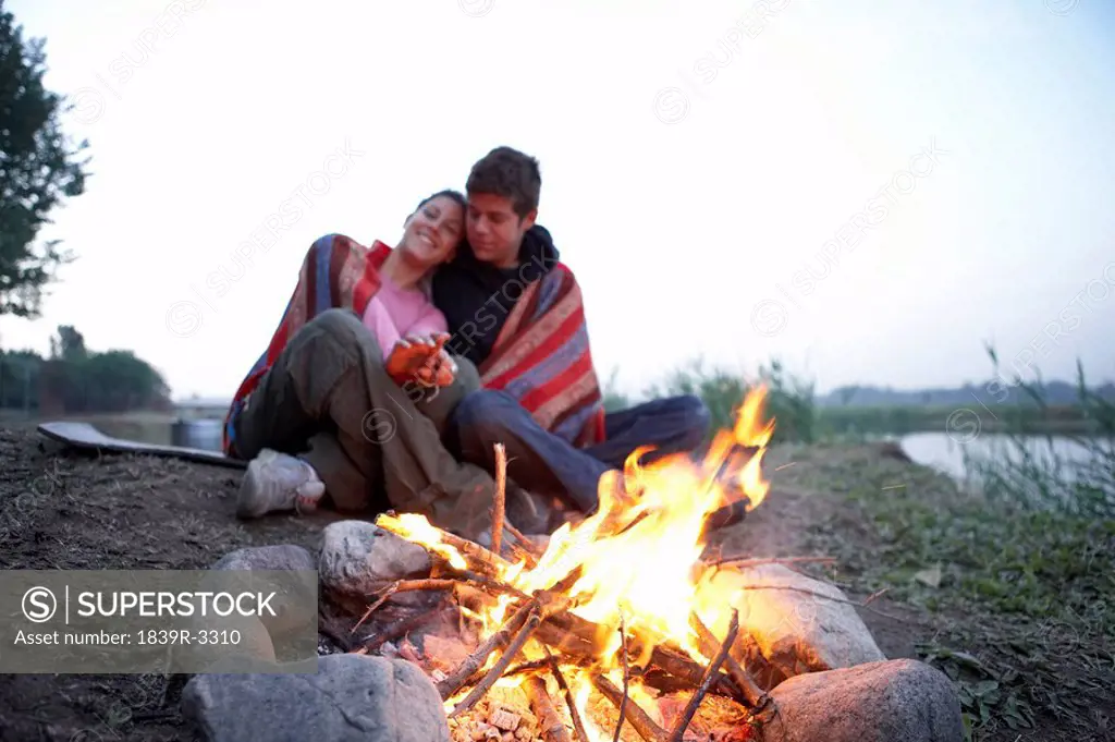 Young Couple Camping In Front Of Fire