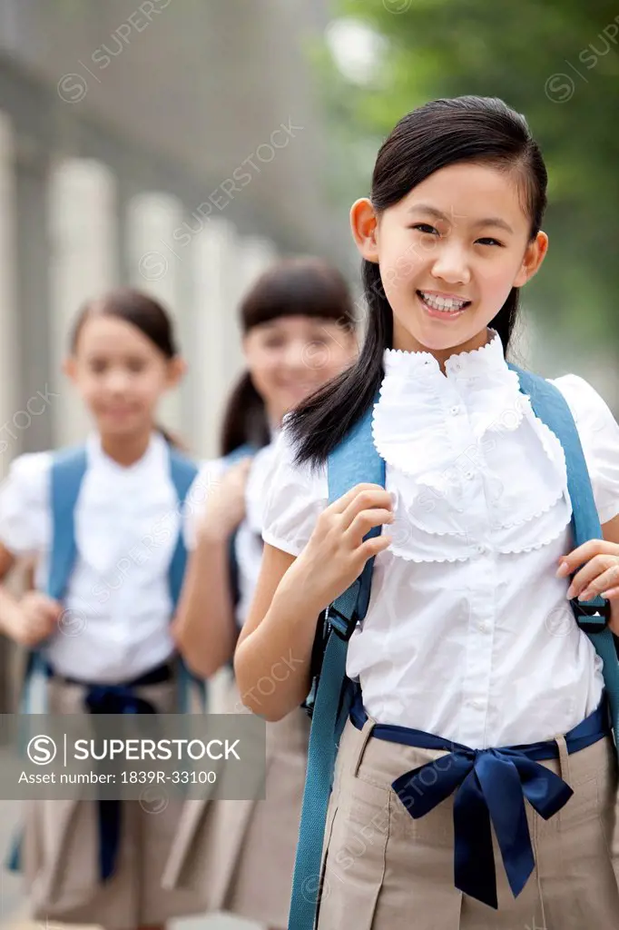 Cute schoolgirl in uniform and her friends in background