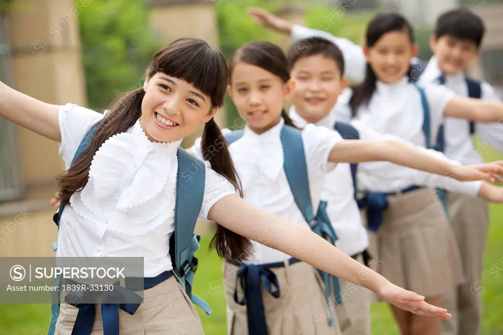 Lively schoolchildren in uniform playing at school yard