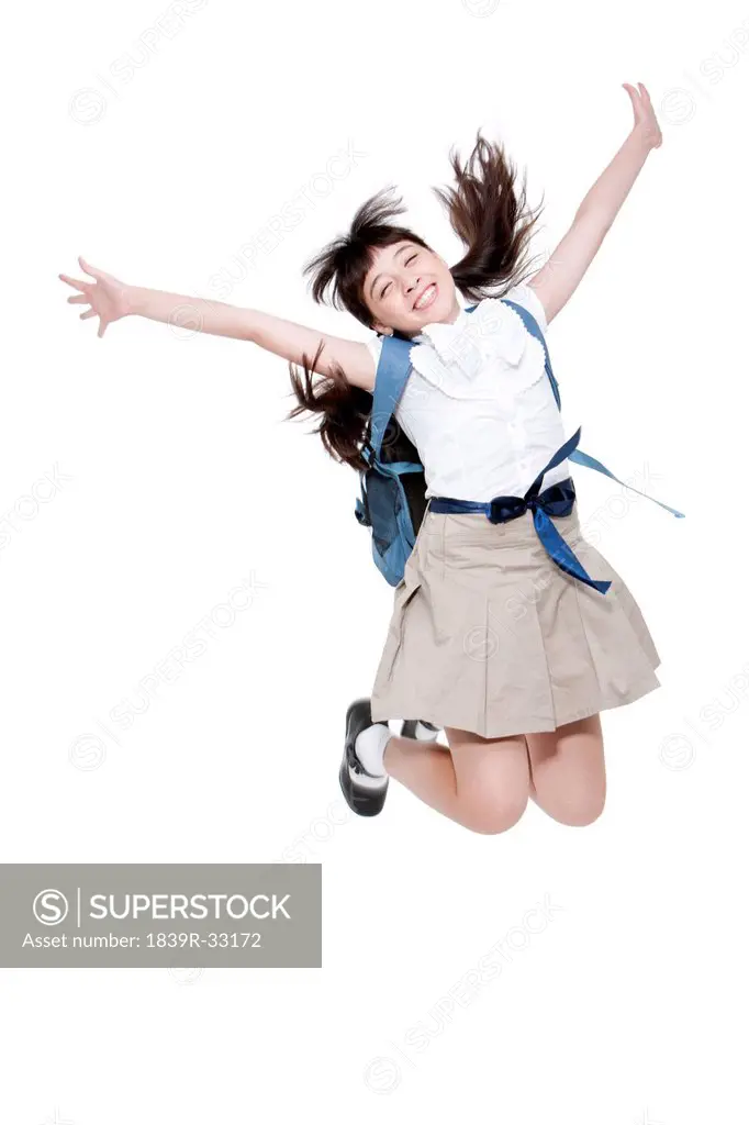 Excited schoolgirl jumping in mid-air with schoolbag on the back