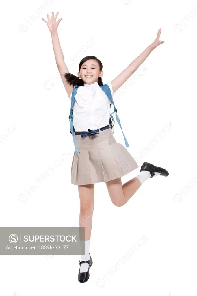 Excited schoolgirl jumping with schoolbag on the back