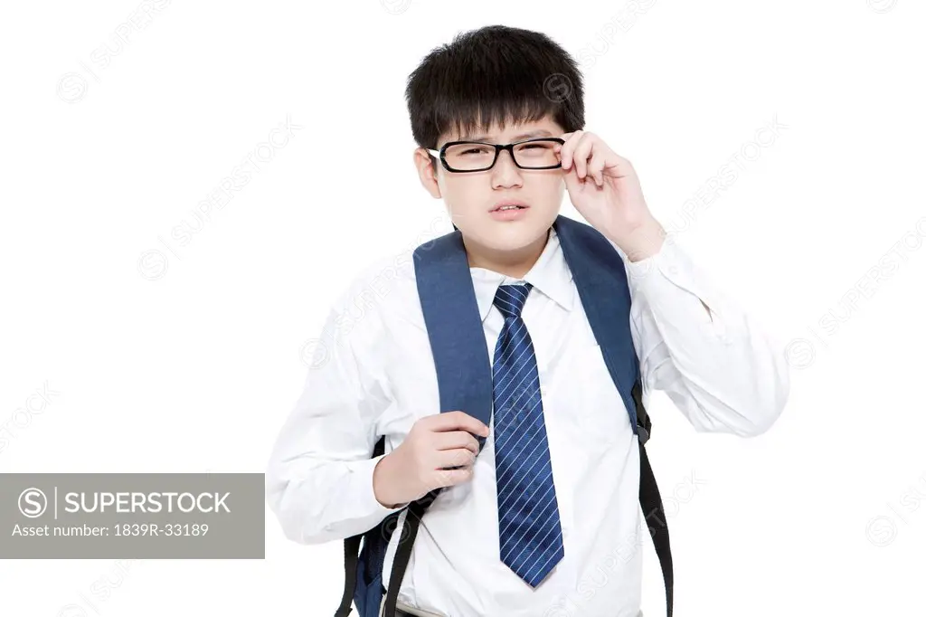 Nearsighted schoolboy having trouble seeing things clearly adjusting his glasses