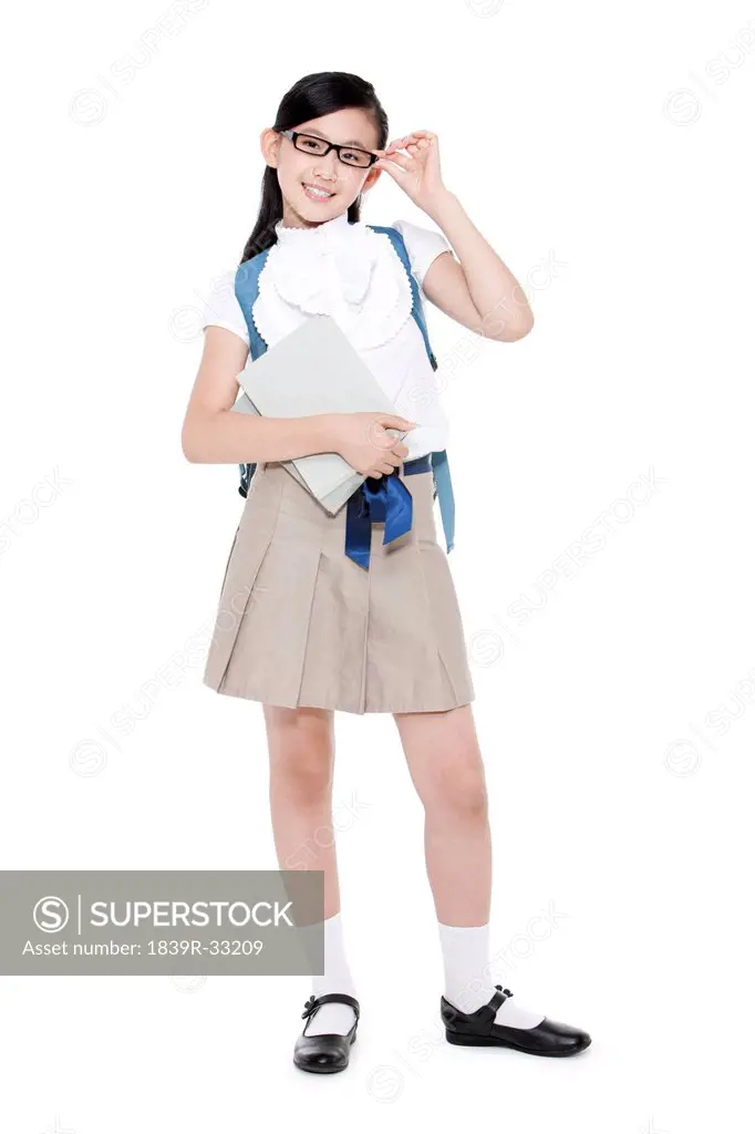 Pretty schoolgirl adjusting her glasses with books and schoolbag