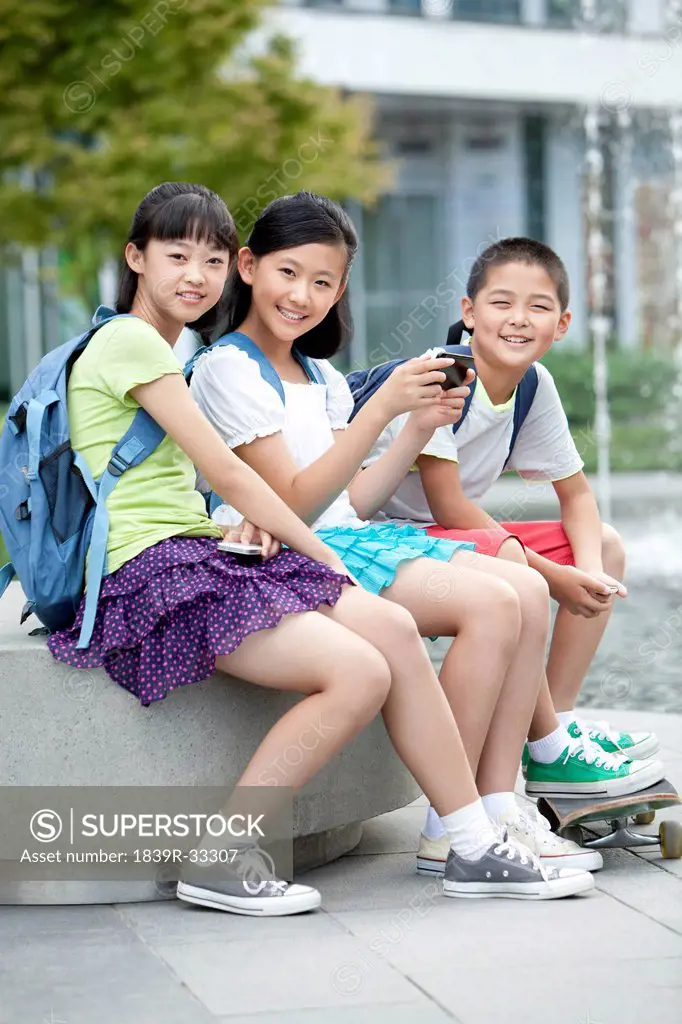 Portrait of schoolchildren playing smart phones together