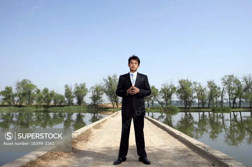Businessman Standing Next To A Lake On A Bridge