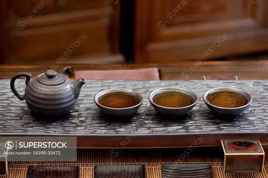 Chinese teapot and tea cups in a row