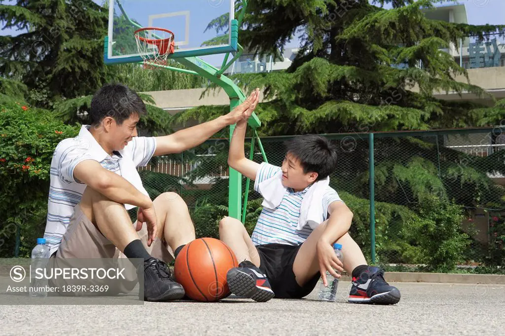 Father And Son High Fiving After Basketball Game
