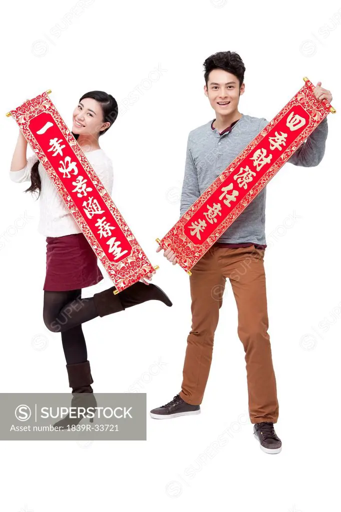 Happy young couple holding Chinese traditional couplets