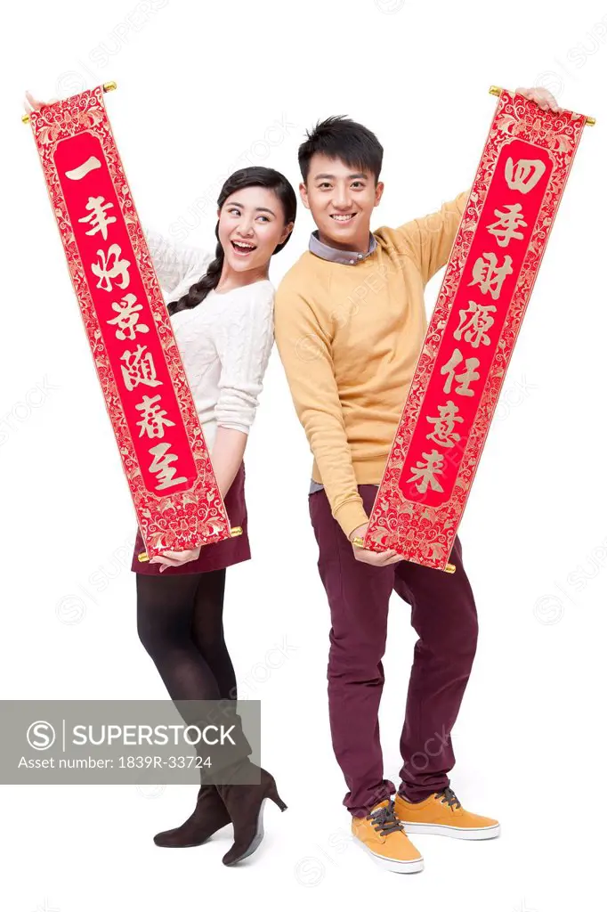 Sweet young couple holding Chinese traditional couplets