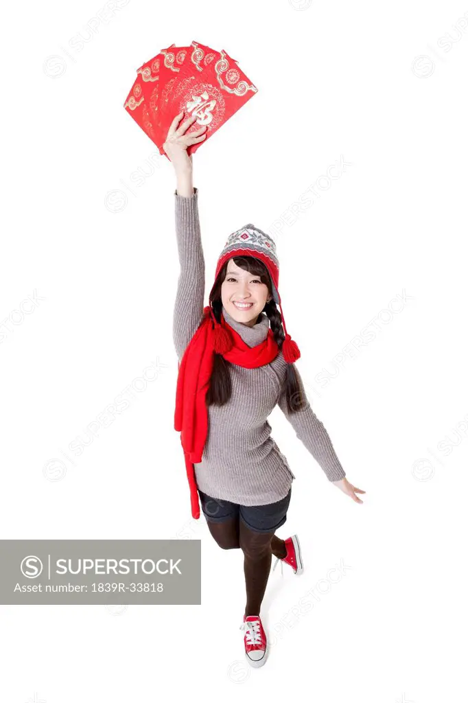 Joyful young woman holding aloft red envelops for Chinese New Year