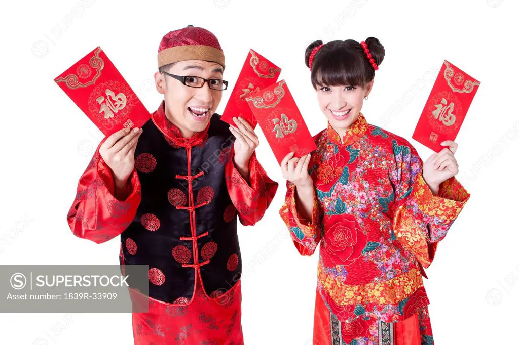 Young couple holding red pockets in traditional Chinese clothing