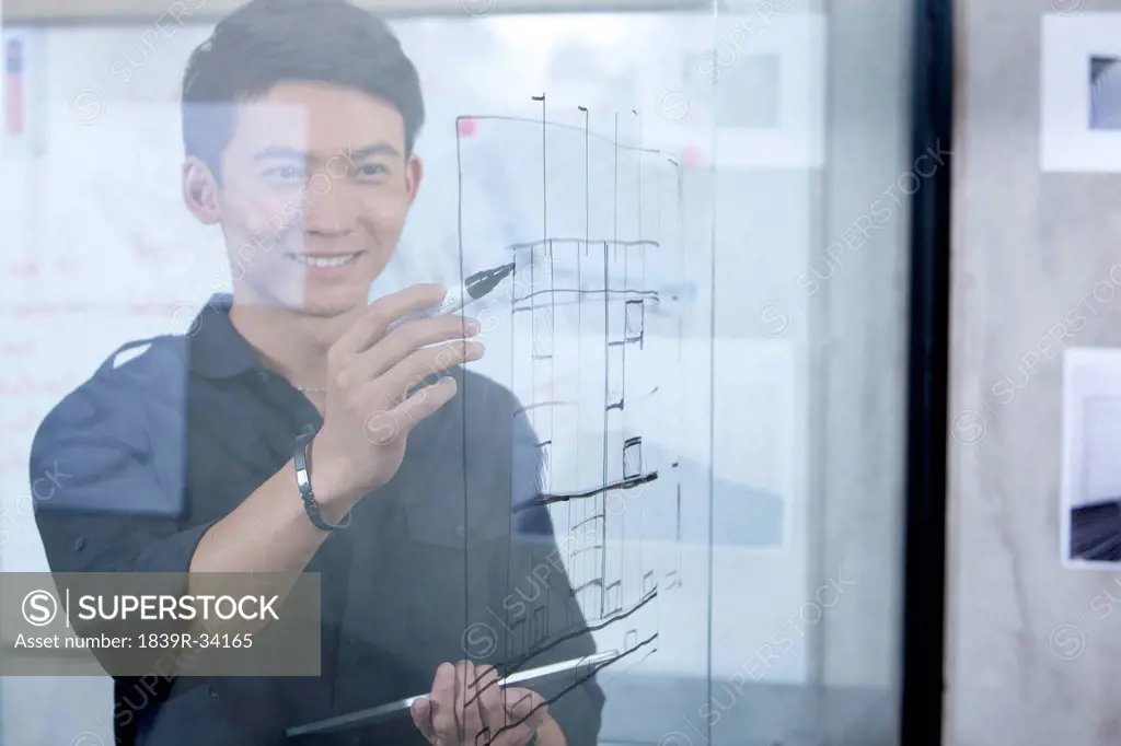 Male designer drawing sketch on glass wall