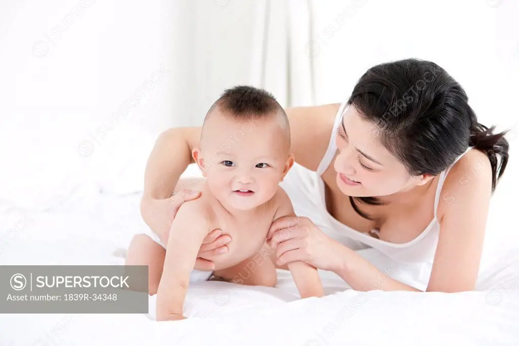 Gentle mother and cute baby in bedroom