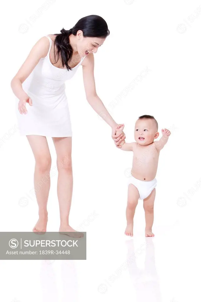 Young mother teaching baby walking