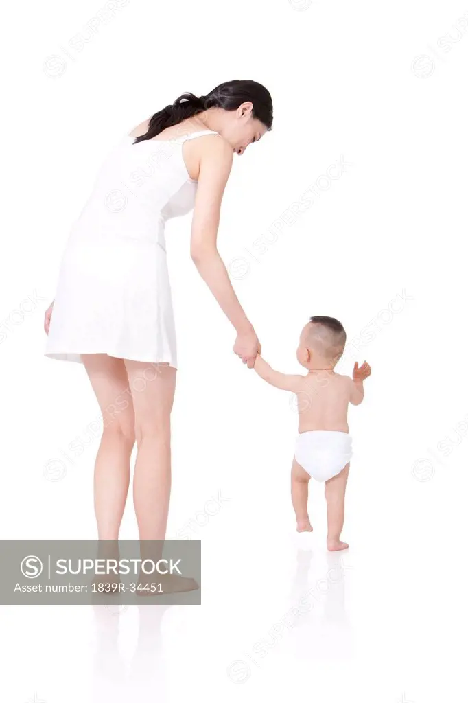Young mother teaching baby walking