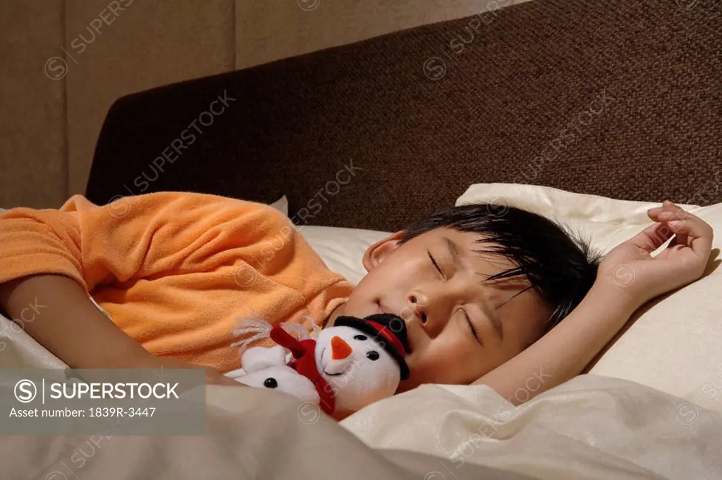 Boy Asleep In Bed With Toy Snowman