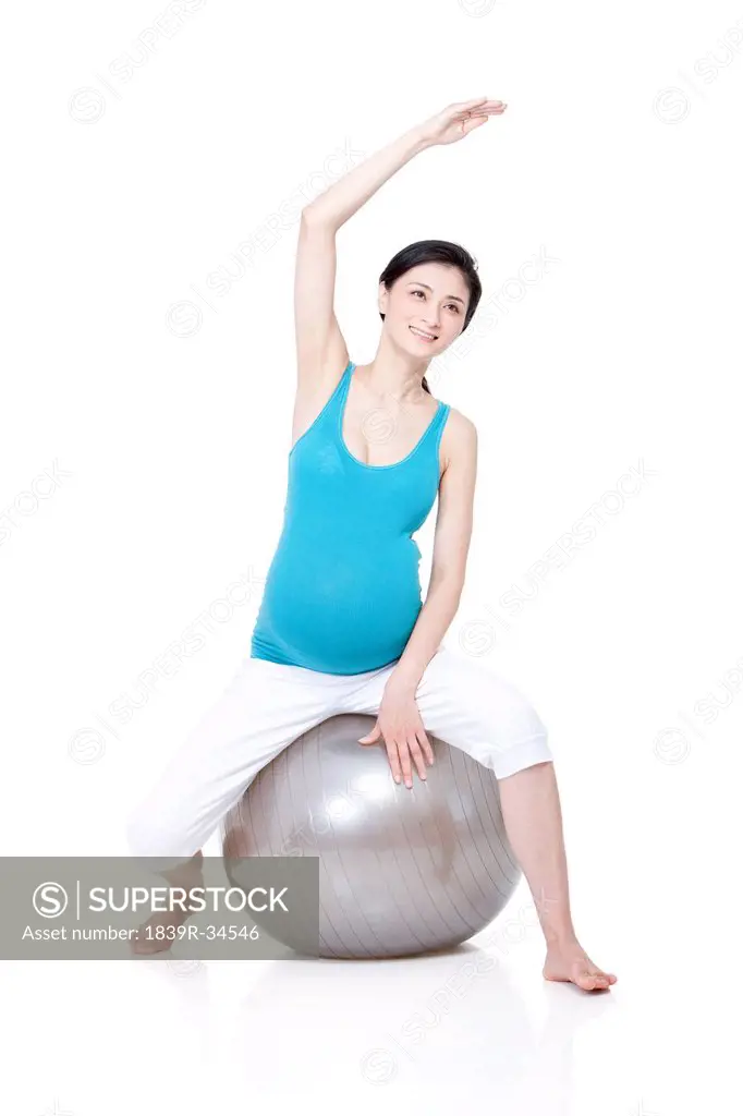 Young pregnant woman sitting on fitness ball