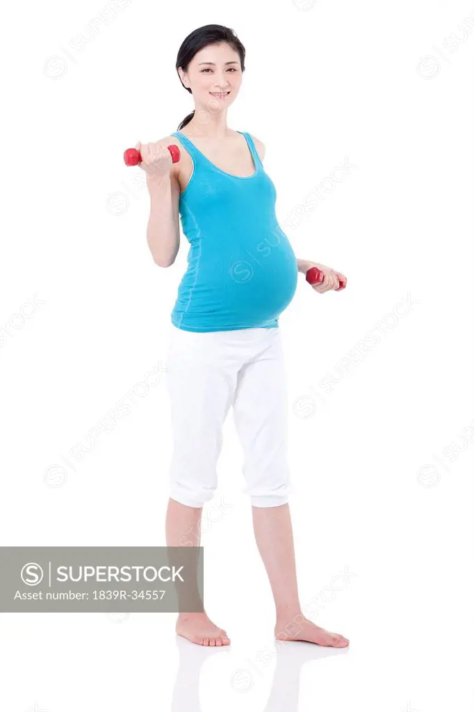 Young pregnant woman exercising with dumbbells