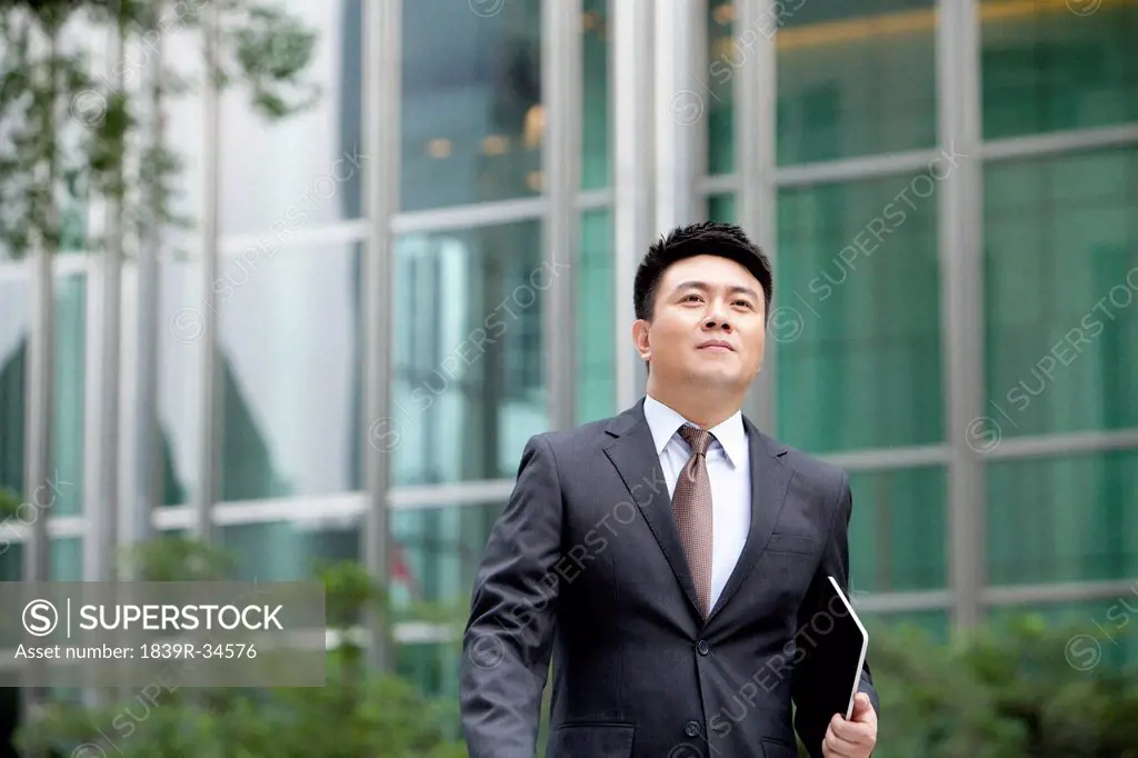 Confident mature businessman walking with digital tablet in hand, Hong Kong