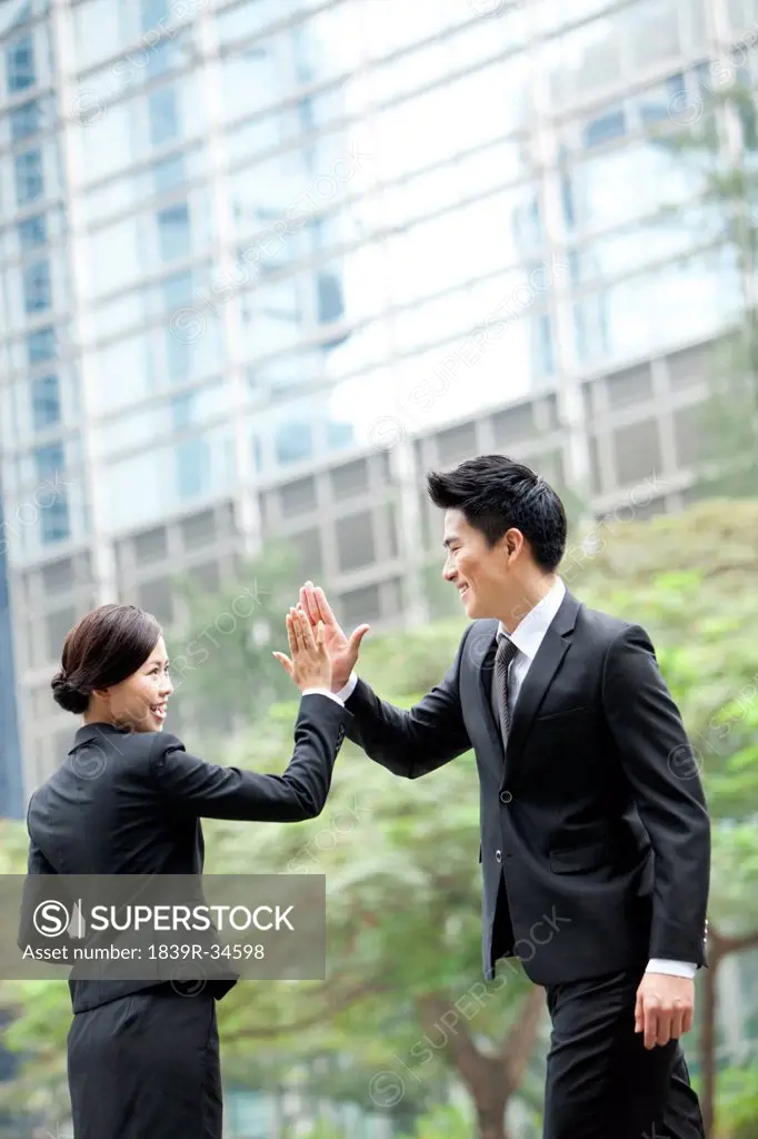 Excited business coworkers doing high-five outside a building, Hong Kong