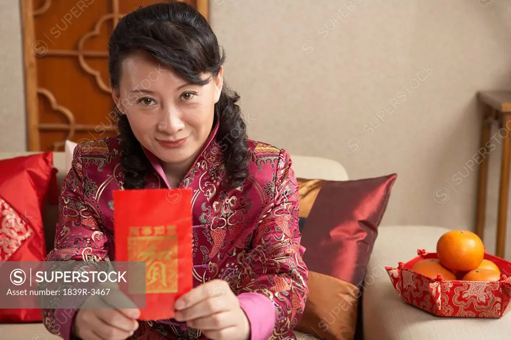 Woman Sitting On Couch Holding Out Red Chinese Paper