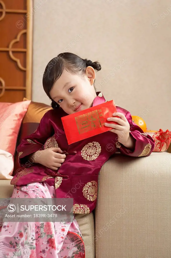 Young Girl Happily Opening Present In Traditional Clothing