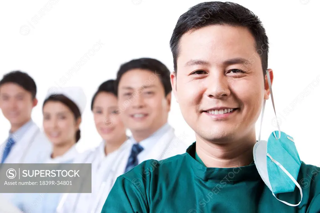 Portrait of happy male surgeon with medical team in background