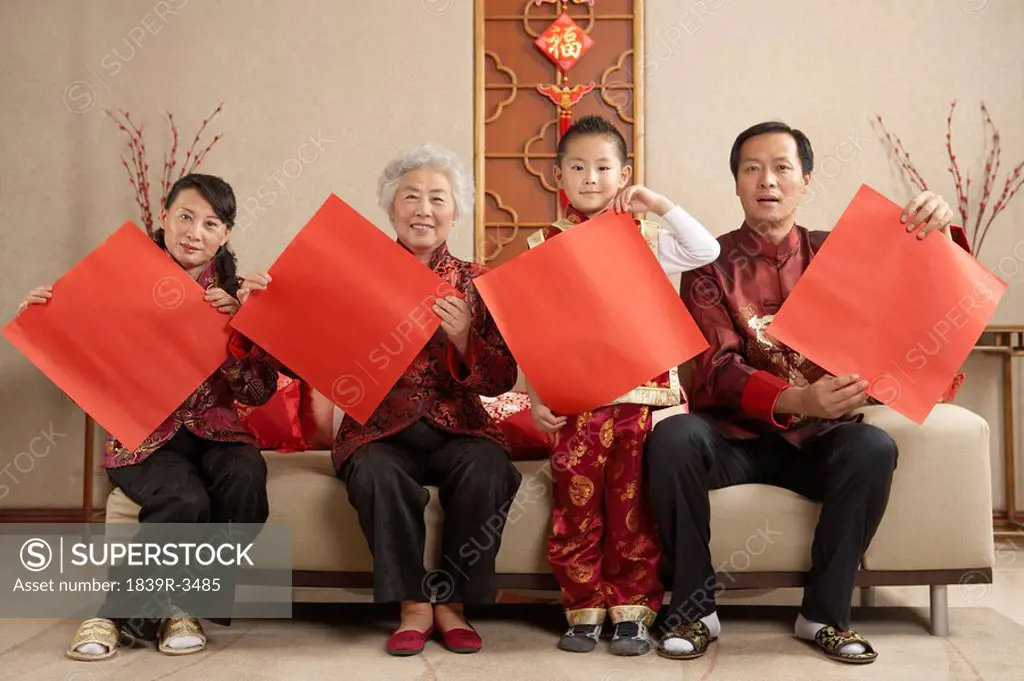 Family In Traditional Clothing Holding Up Paper