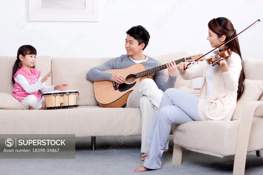 Joyful young family playing musical instruments at home