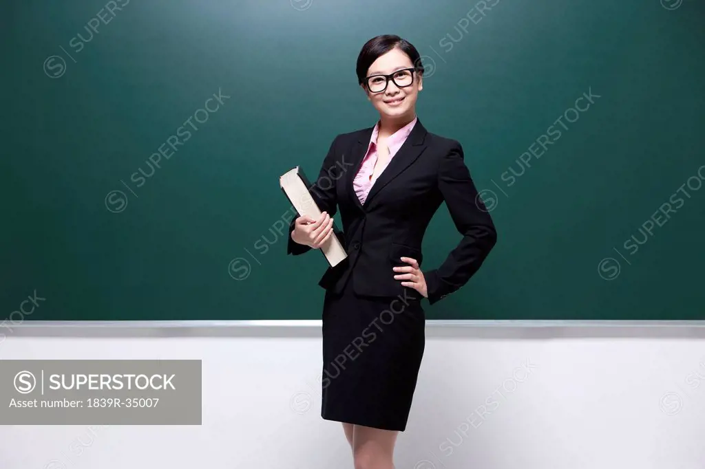 Professional female teacher hand on hip in classroom