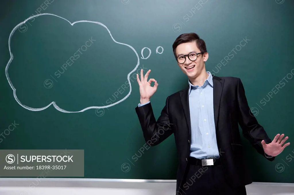 Professional male teacher doing OK sign in classroom