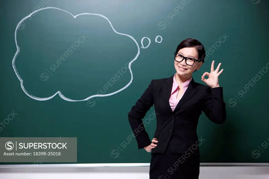 Professional female teacher doing OK sign in classroom
