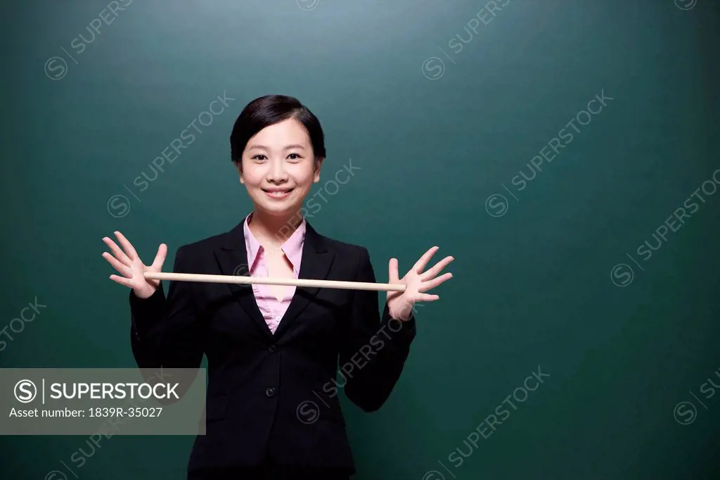 Happy female teacher holding teacher's pointer in classroom