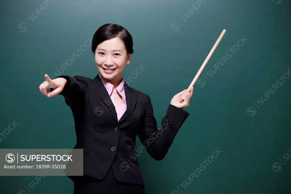 Cheerful female teacher pointing forward in classroom