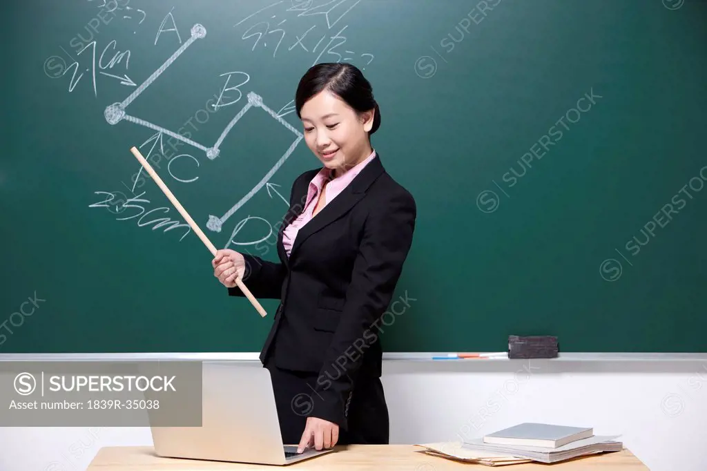 Female teacher using laptop in classroom