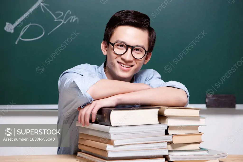 Happy male teacher with textbooks in classroom