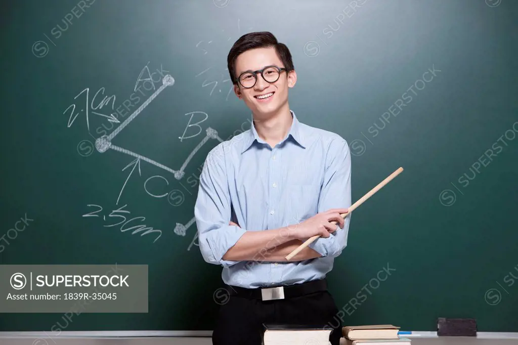 Portrait of male teacher arms crossed in classroom